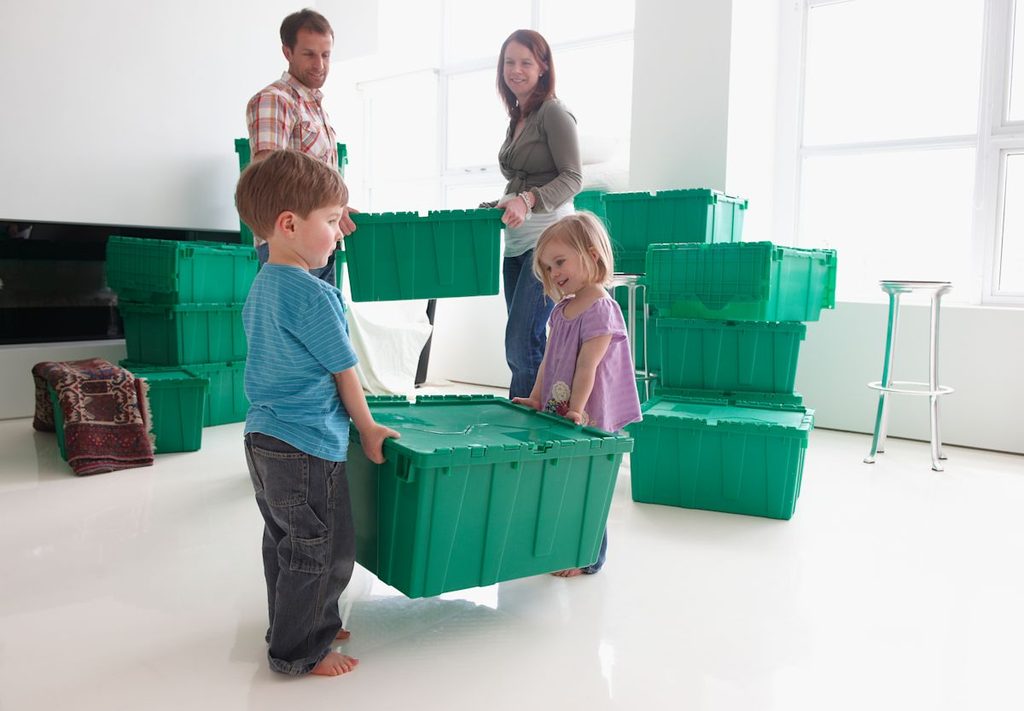Family unpacking green moving crates in a bright new home