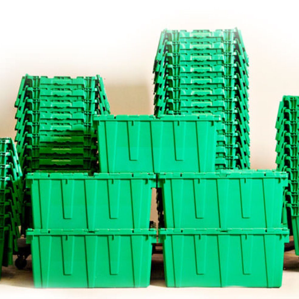 Stacks of clean green reusable moving crates in the Queen City Crates warehouse